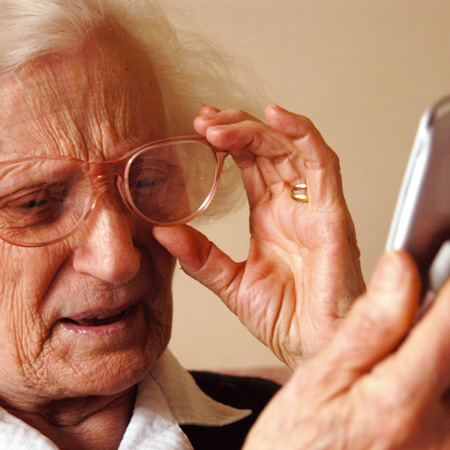 Signora anziana legge il suo cellulare.